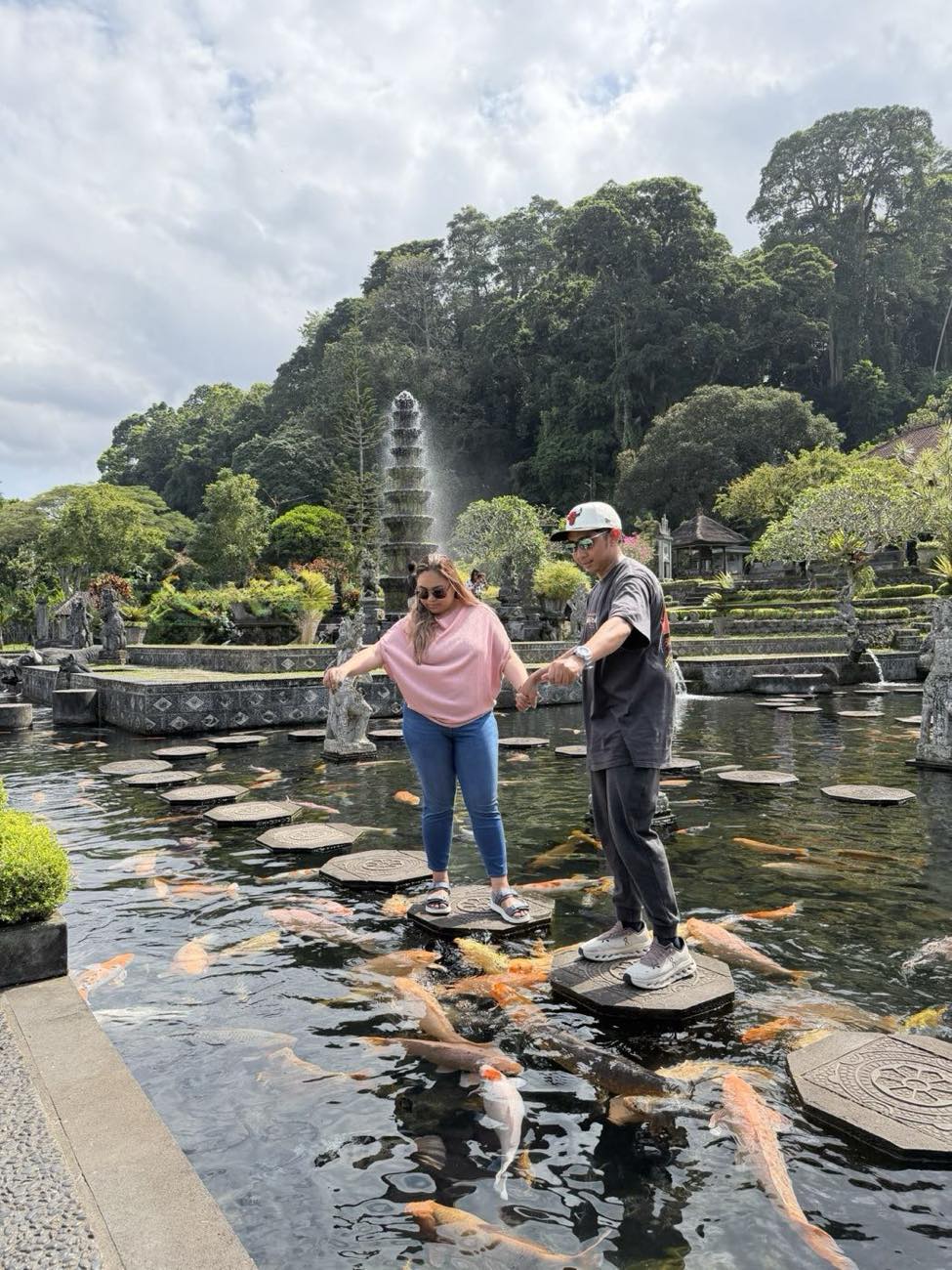 Couple crossing the stepping stones over the koi pond at Tirta Gangga