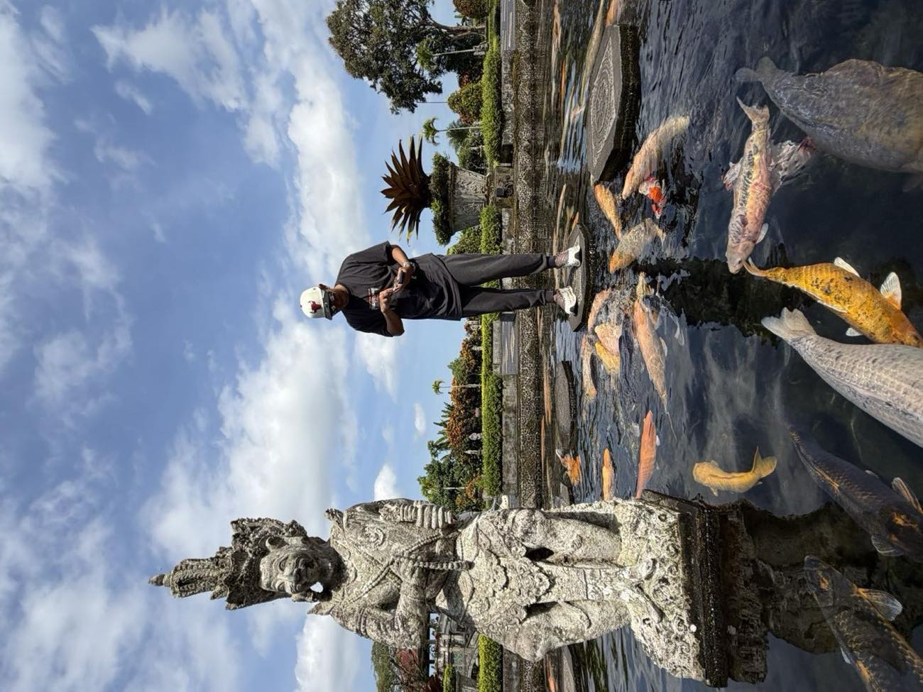 Carved stone figure beside the koi pond at Tirta Gangga